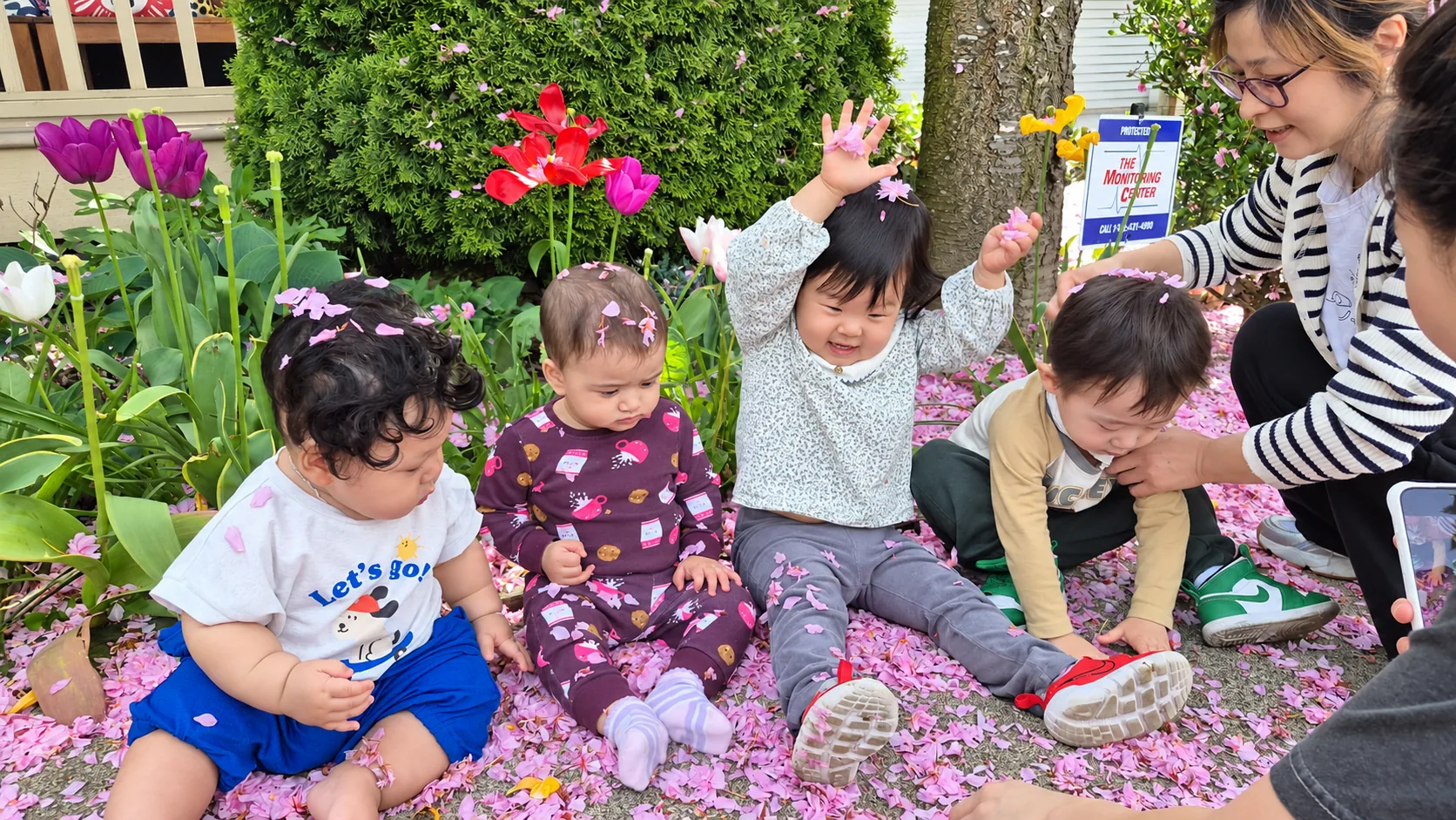 Children and their educator exploring fallen petals in the garden